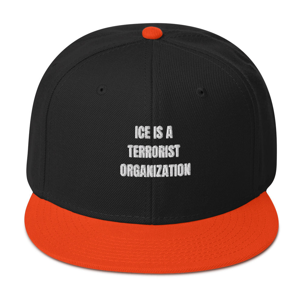 Snapback Hat featuring bold text "ICE IS A TERRORIST ORGANIZATION", black body and orange visor.