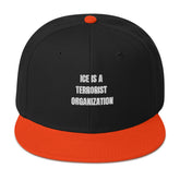 Snapback Hat featuring bold text "ICE IS A TERRORIST ORGANIZATION", black body and orange visor.